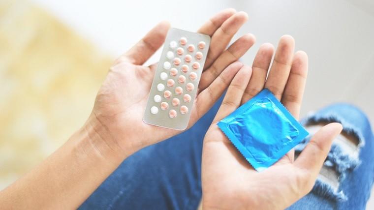 kobieta zastanawia się, którą formę antykoncepcji wybrać - prezerwatywę czy tabletki antykoncepcyjne