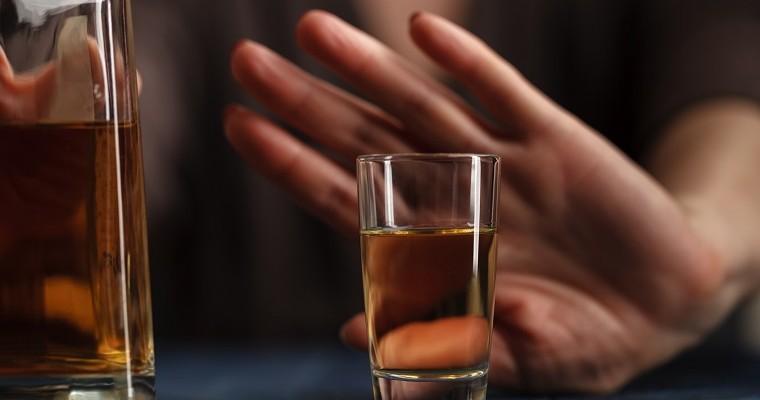 Kobieca ręka przed szkalnką z alkoholem odmawia