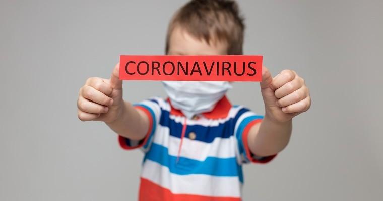 Dziecko, które trzyma kartkę z napisem koronawirus 