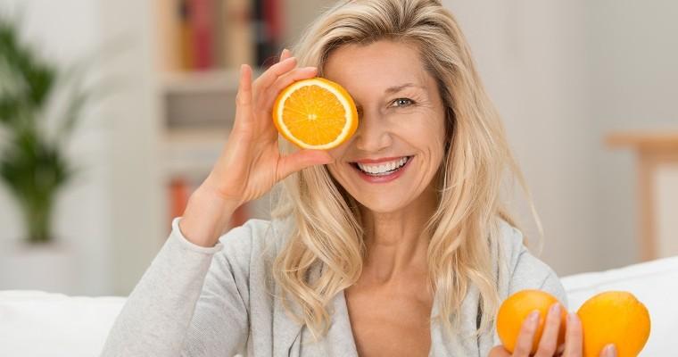 Uśmiechnięta kobieta, która trzyma pomarańczę