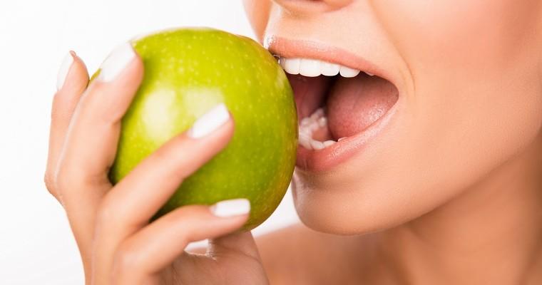 Kobieta, która ma mocne zęby i je jabłko 
