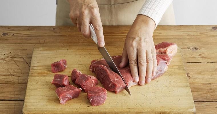 Kobieta lub mężczyzna kroi mięso na desce kuchennej. 