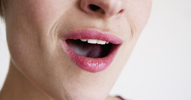 Kobieta dotyka językiem swojego podniebienia. Zbliżenie na usta. 