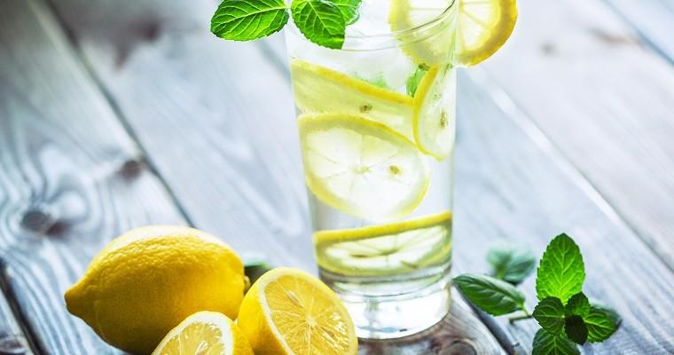 Lemoniada - woda z cytryną w szklance, obok cytryna.