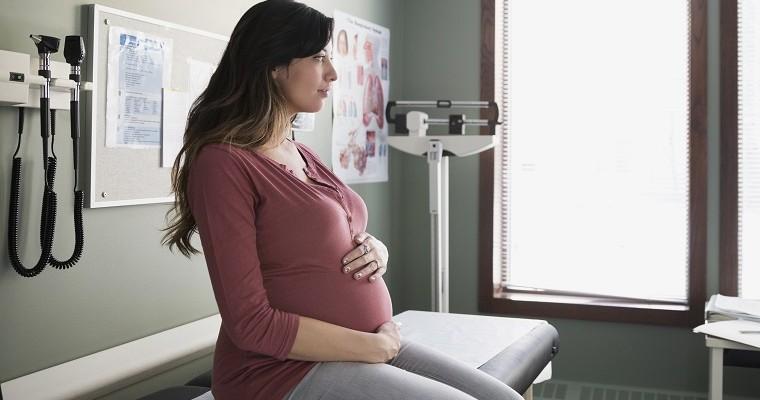 Kobieta w ciąży siedzi w gabinecie lekarskim. 