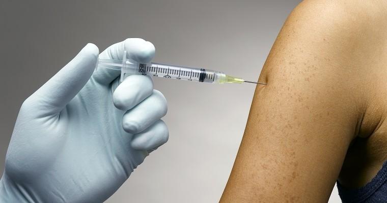 Szczepienie - pielęgniarka podaje dawkę szczepionki w ramię. 