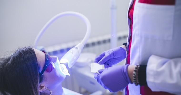 stomatolog wykonuje zabieg wybielenia zębów lampą ultrafioletową 