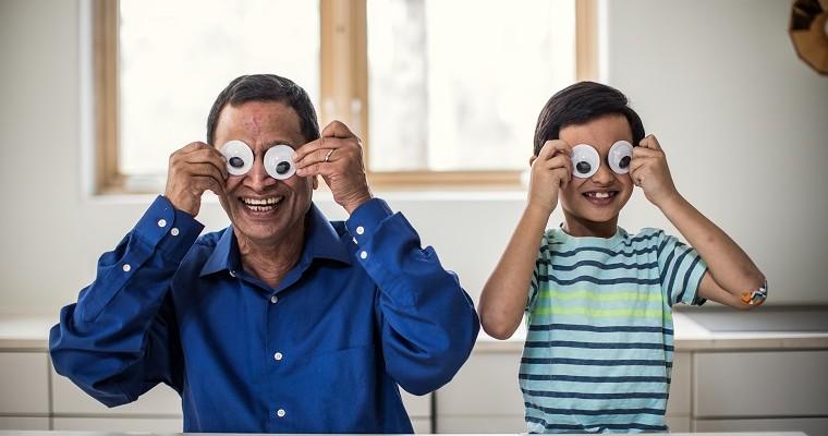tata i syn bawią się, nakładają sobie białe okrągłe kartki na oczy. 