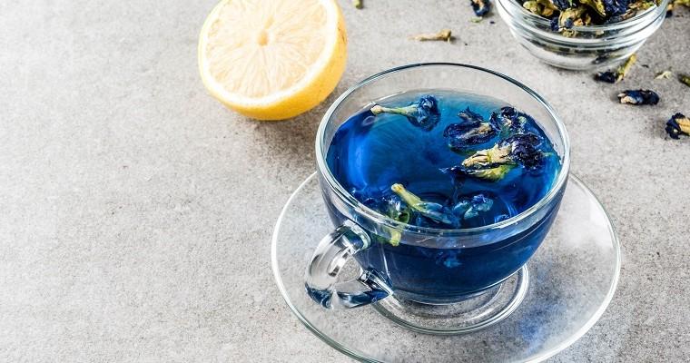niebieska herbata w szklanej filiżance leży na szarym blacie 
