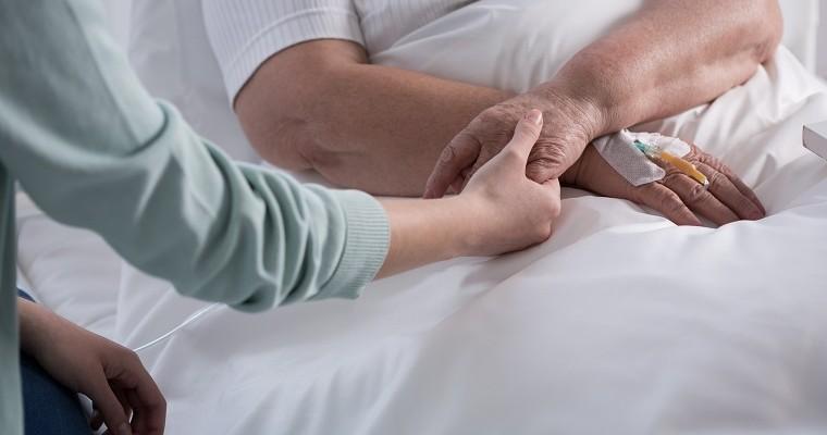 Kobieta trzyma za rękę chorego w szpitalu