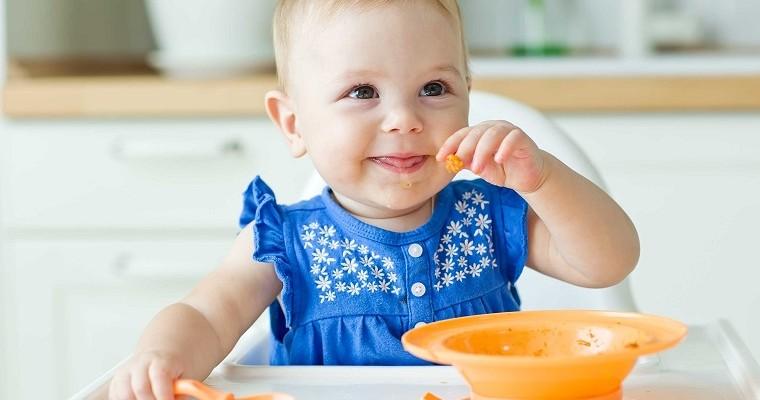 Dziecko w niebieskim ubraniu je zupę. 
