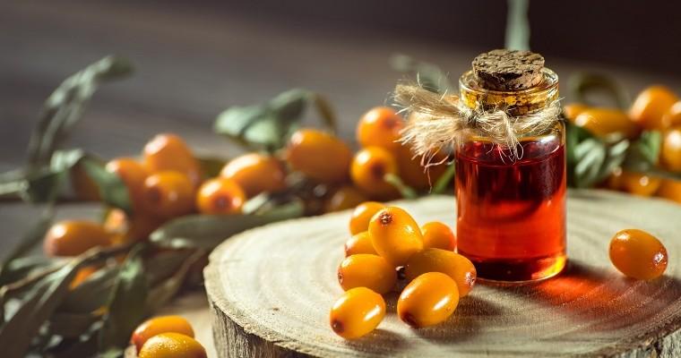 Olejek w buteleczce i pomarańczowe owoce rokitnika