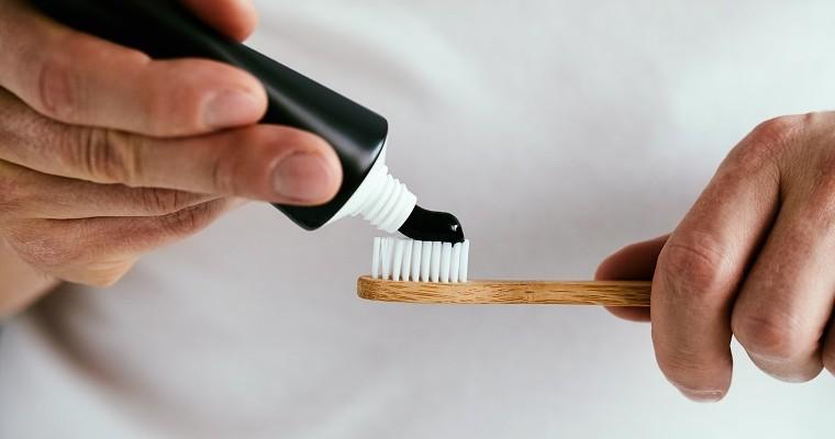 Osoba, która myje zęby pastą z aktywnym węglem 